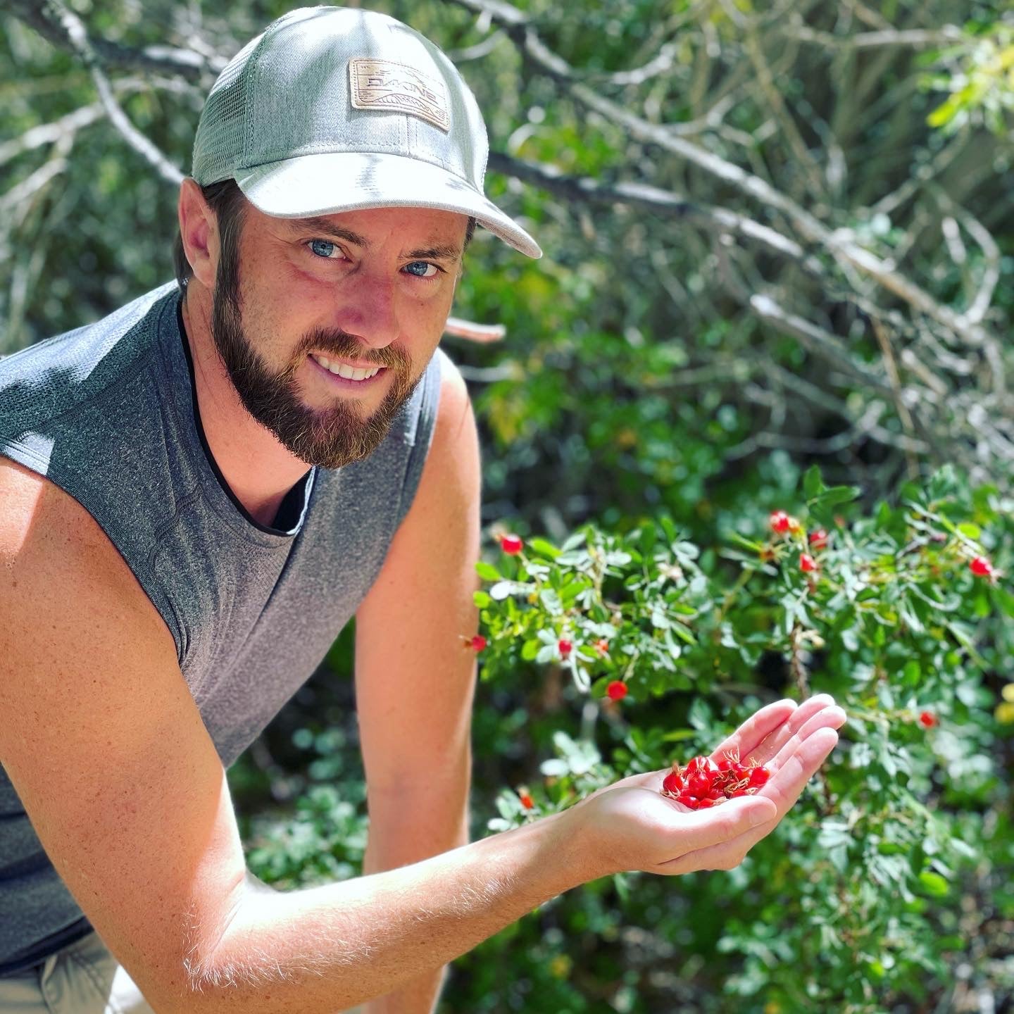 Man holding red berries in his hand with a natural background of greenery